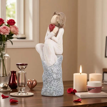 A girl sitting and holding a heart Valentine’s Day gift
