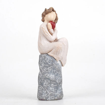 A girl sitting and holding a heart Valentine’s Day gift